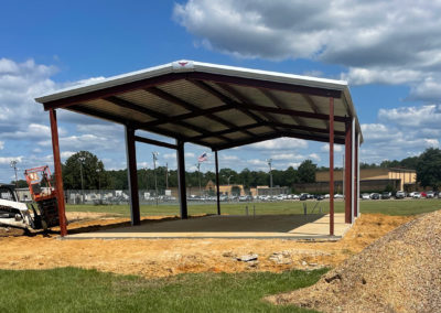 Image shows A Metal framed Building with a closed roof and open sides located at Amory Park | Phoenix Building Solutions | Metal Buildings | Barndominiums | Pole Barns | Custom Metal Orders