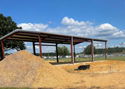 Image shows A Metal framed Building with a closed roof and open sides located at Amory Park | Phoenix Building Solutions | Metal Buildings | Barndominiums | Pole Barns | Custom Metal Orders