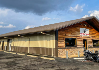 Image shows a mixed color Metal framed Building with brick and wood front For Revelations Outdoors | Phoenix Building Solutions | Metal Buildings | Barndominiums | Pole Barns | Custom Metal Orders
